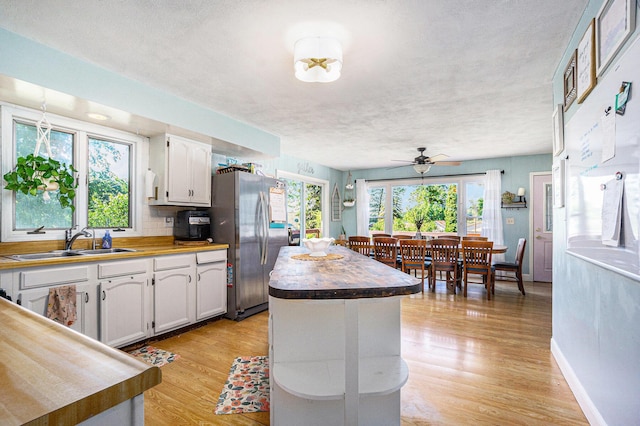 15645 Rich Ln, Hickory Corners, MI 49060 - kitchen featuring freestanding refrigerator, white cabinetry, light wood-style flooring, ceiling fan, and a textured ceiling