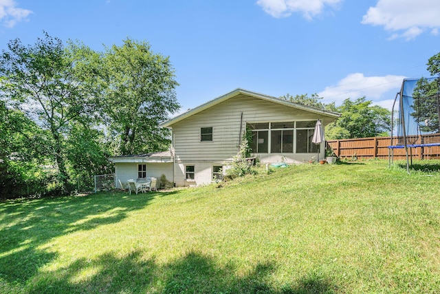 15645 Rich Ln, Hickory Corners, MI 49060 - back of house featuring a trampoline, a fenced backyard, and a sunroom