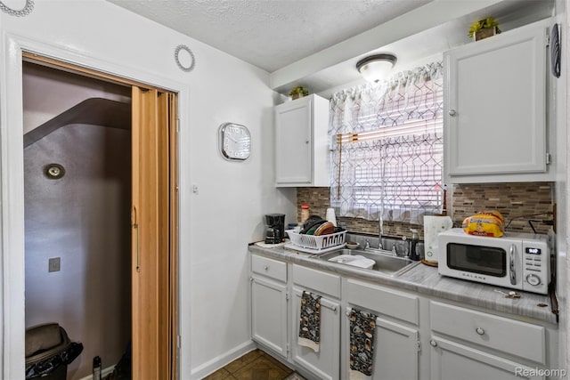 19359 Montrose St, Detroit, MI 48235 - kitchen with backsplash, light countertops, white cabinets, a textured ceiling, and dark tile patterned floors