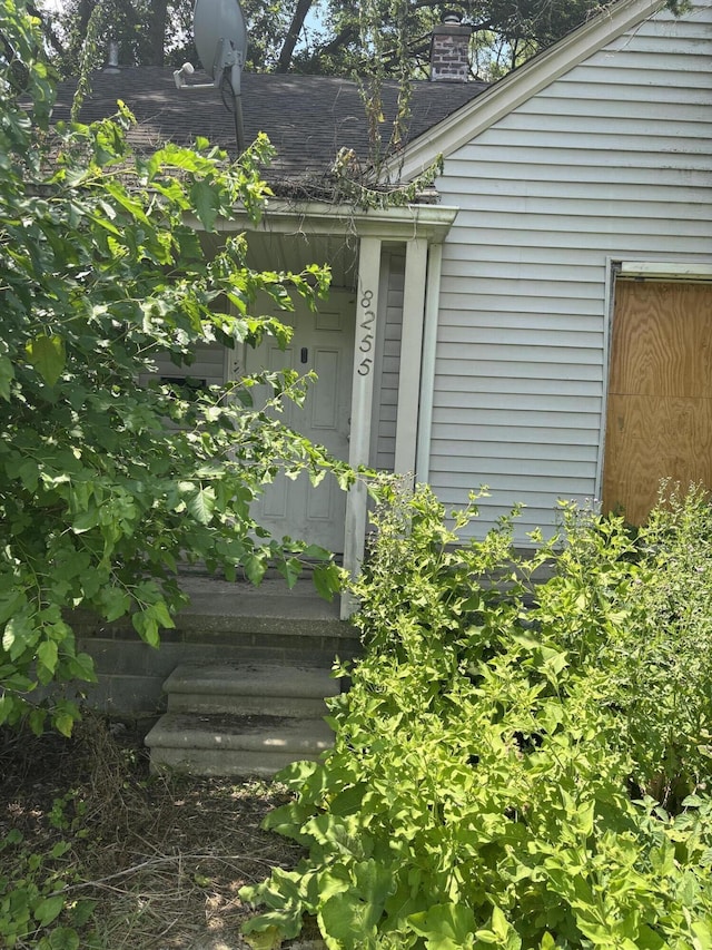 8255 Marlowe St, Detroit, MI 48228 - view of exterior entry with a shingled roof and a chimney