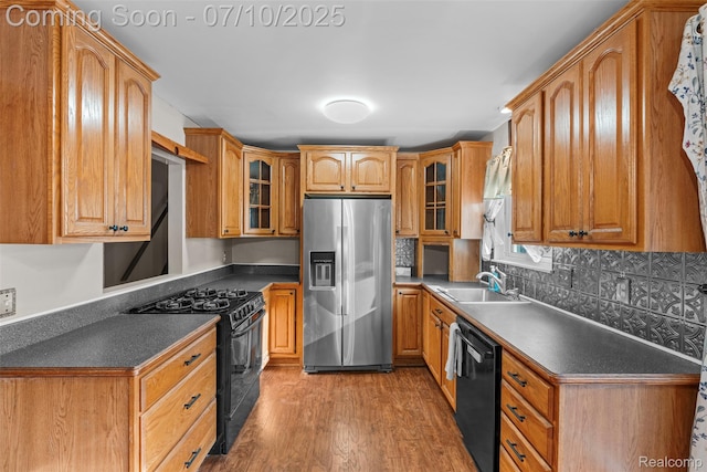 1560 Mercedes St, West Bloomfield, MI 48324 - kitchen featuring black appliances, dark countertops, light wood-style flooring, and glass insert cabinets