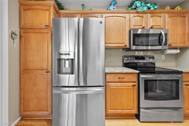 50323 Highpoint Ct, Macomb, MI 48044 - kitchen featuring appliances with stainless steel finishes, decorative backsplash, light stone counters, and light wood-type flooring