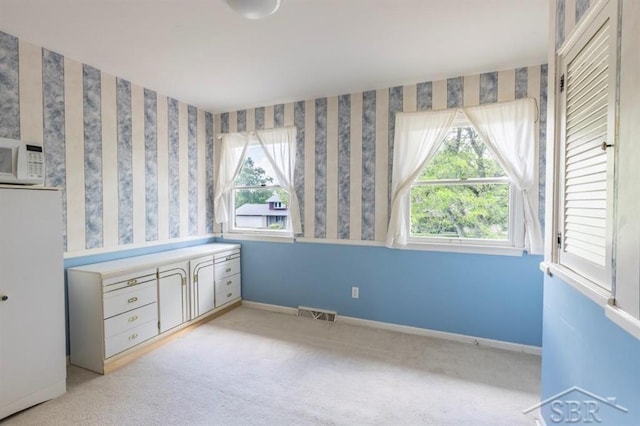 595 Stoneham Rd, Saginaw, MI 48638 - unfurnished bedroom with multiple windows, light carpet, and freestanding refrigerator