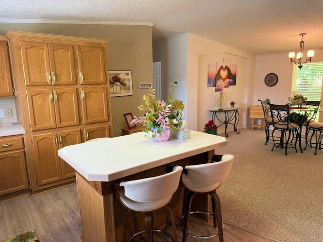 7878 Schooner Ln, Canadian Lakes, MI 49346 - kitchen featuring a textured ceiling, a chandelier, a kitchen island, light countertops, and a breakfast bar