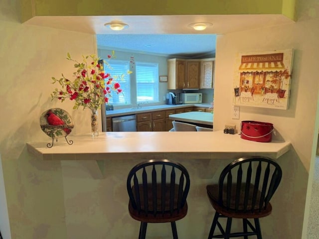 7878 Schooner Ln, Canadian Lakes, MI 49346 - kitchen featuring white microwave, dishwasher, a breakfast bar, and a peninsula