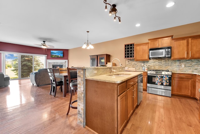 5196 Mesa Dr, Michigan, MI 48316 - kitchen featuring appliances with stainless steel finishes, a breakfast bar, tasteful backsplash, a lit fireplace, and a ceiling fan
