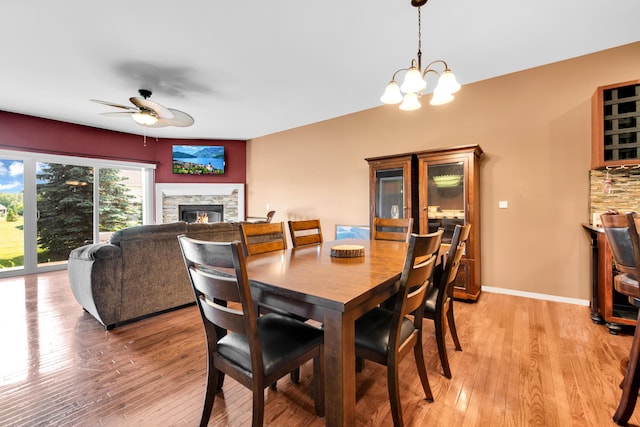 5196 Mesa Dr, Michigan, MI 48316 - dining area featuring a fireplace, a ceiling fan, light wood-style floors, and a chandelier