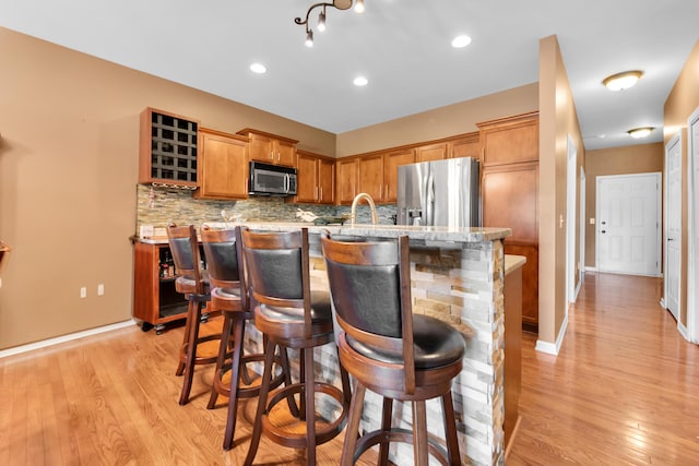 5196 Mesa Dr, Michigan, MI 48316 - kitchen with appliances with stainless steel finishes, backsplash, light wood-type flooring, and a kitchen island with sink