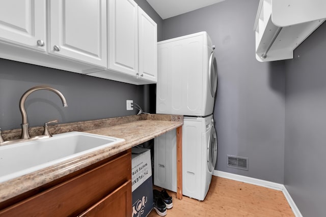 5196 Mesa Dr, Michigan, MI 48316 - washroom with stacked washer / dryer, cabinet space, and light wood-style flooring