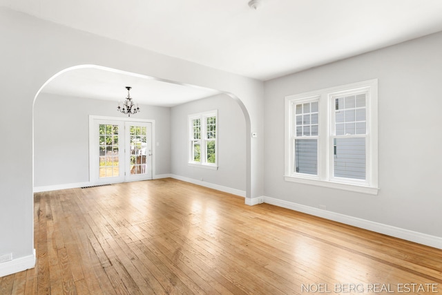 1307 Waverly Ave, Grand Haven, MI 49417 - empty room with arched walkways, light wood finished floors, and a chandelier