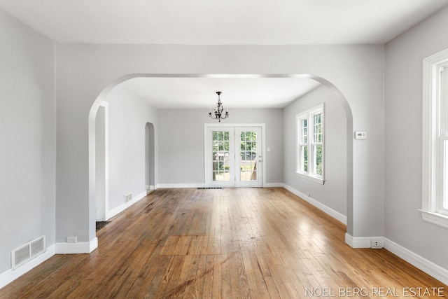 1307 Waverly Ave, Grand Haven, MI 49417 - empty room featuring arched walkways, hardwood / wood-style floors, and a chandelier