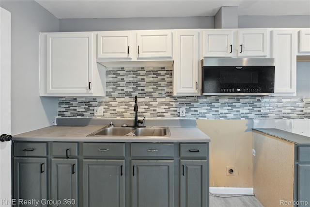 25143 Fern St, Roseville, MI 48066 - kitchen with gray cabinets, stainless steel microwave, white cabinets, decorative backsplash, and light countertops