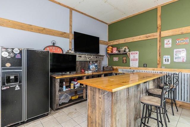 6671 E 136th St, Sand Lake, MI 49343 - kitchen featuring black fridge, wooden counters, tile patterned flooring, and a kitchen bar
