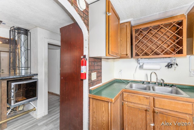 510 La Grave Ave SE, Grand Rapids, MI 49503 - kitchen with a textured ceiling, light wood-style flooring, brown cabinetry, and arched walkways