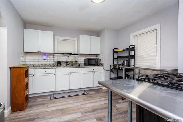3602 Chatsworth St, Detroit, MI 48224 - kitchen with black microwave, white cabinetry, backsplash, and light wood finished floors