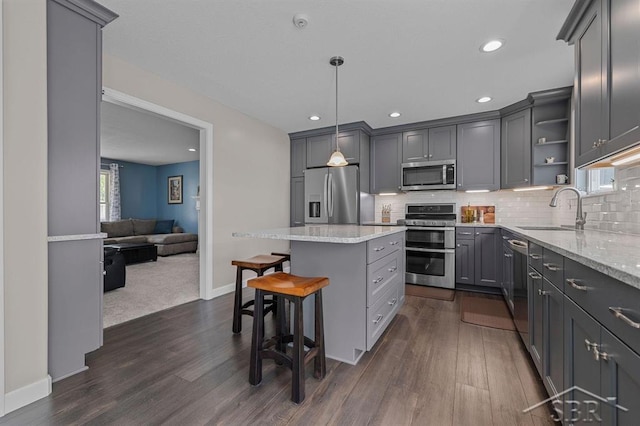 936 Appaloosa Pass, Auburn, MI 48611 - kitchen with stainless steel appliances, gray cabinetry, open shelves, a center island, and a kitchen breakfast bar