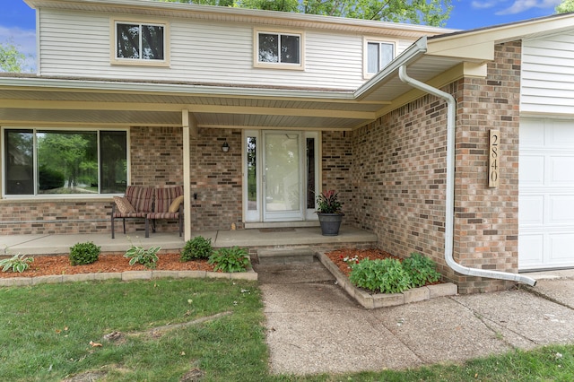 2840 Tuebingen Pkwy, Ann Arbor, MI 48105 - view of exterior entry with covered porch, an attached garage, and brick siding