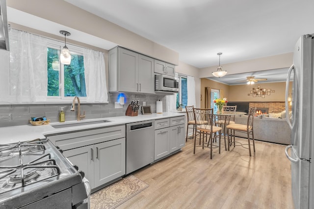 2840 Tuebingen Pkwy, Ann Arbor, MI 48105 - kitchen with appliances with stainless steel finishes, gray cabinetry, light wood-type flooring, tasteful backsplash, and light countertops