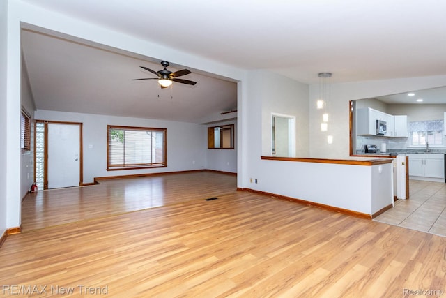 30604 Ann Arbor Trl, Westland, MI 48185 - unfurnished living room with light wood-style flooring, plenty of natural light, ceiling fan, and vaulted ceiling