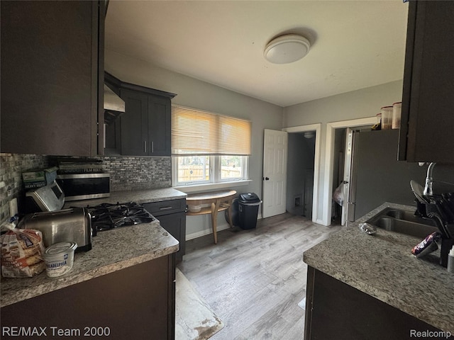 6815 Mettetal St, Detroit, MI 48228 - kitchen with backsplash, stainless steel microwave, light wood-style flooring, and range hood