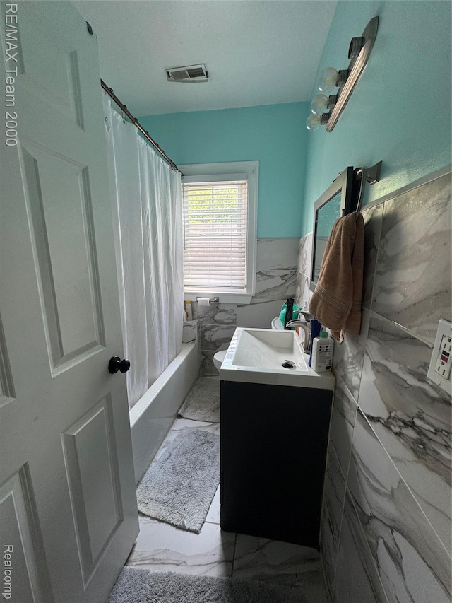 6815 Mettetal St, Detroit, MI 48228 - bathroom with marble finish floors, vanity, tile walls, shower / bath combo with shower curtain, and wainscoting