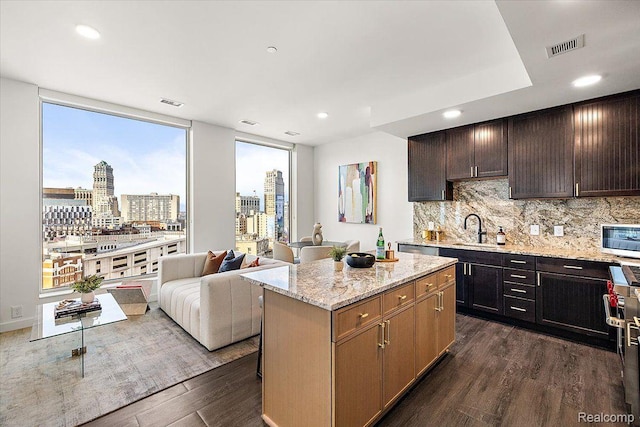 330 Gratiot Ave Unit 1504, Detroit, MI 48226 - kitchen featuring dark wood-style flooring, backsplash, light stone counters, open floor plan, and a center island