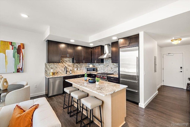 330 Gratiot Ave Unit 1504, Detroit, MI 48226 - kitchen with high end appliances, wall chimney range hood, dark brown cabinets, open floor plan, and a kitchen breakfast bar