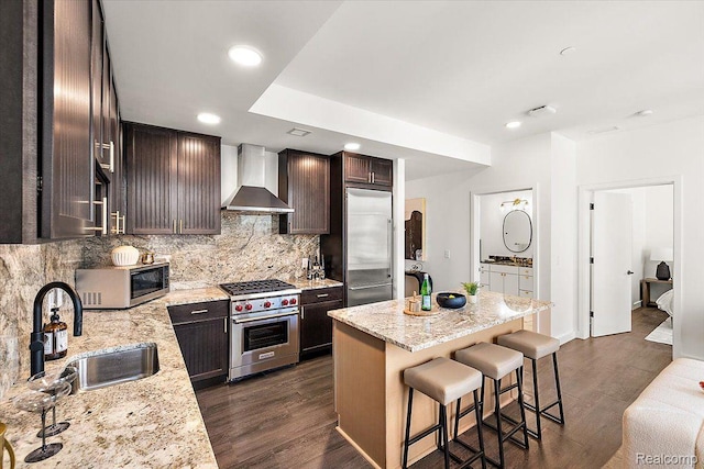 330 Gratiot Ave Unit 1504, Detroit, MI 48226 - kitchen with wall chimney range hood, high end appliances, a kitchen bar, decorative backsplash, and dark wood finished floors