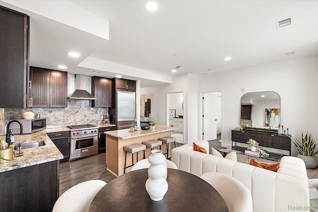 330 Gratiot Ave Unit 1504, Detroit, MI 48226 - kitchen featuring high end appliances, wall chimney range hood, a center island, tasteful backsplash, and open floor plan