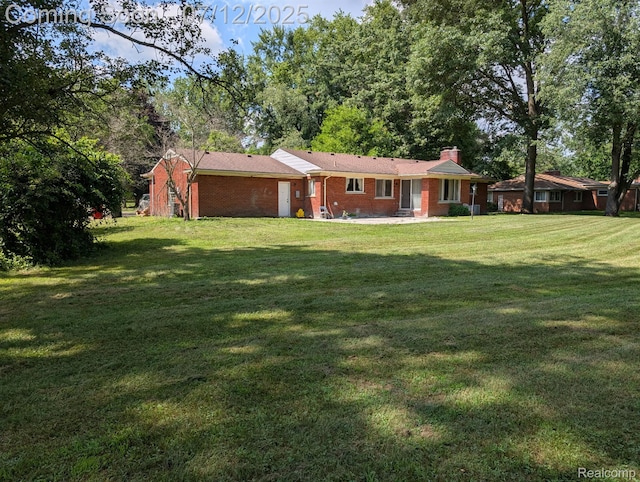 22048 Rougewood Dr, Southfield, MI 48033 - rear view of house featuring a yard, a chimney, and brick siding