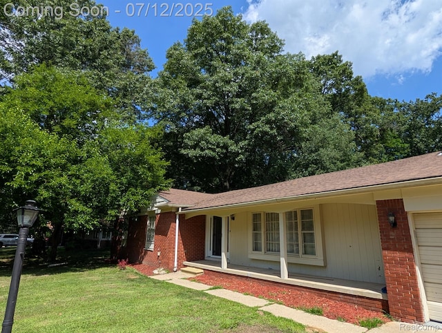 22048 Rougewood Dr, Southfield, MI 48033 - view of front facade featuring brick siding, a front yard, a shingled roof, and a porch