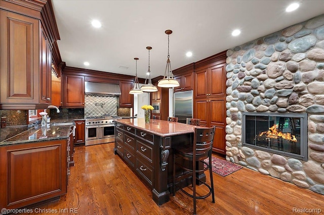 347 Pine Ridge Dr, Bloomfield Hills, MI 48304 - kitchen with built in appliances, wood finished floors, tasteful backsplash, a fireplace, and ventilation hood
