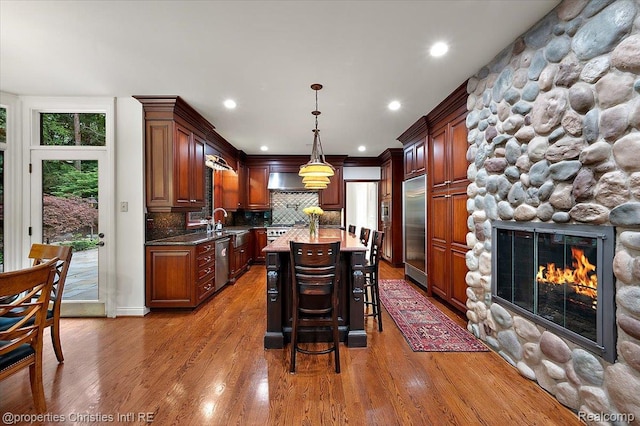 347 Pine Ridge Dr, Bloomfield Hills, MI 48304 - kitchen featuring built in appliances, tasteful backsplash, a stone fireplace, a kitchen breakfast bar, and a center island