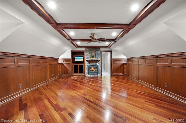 347 Pine Ridge Dr, Bloomfield Hills, MI 48304 - unfurnished living room with light wood-style floors, a ceiling fan, wainscoting, lofted ceiling, and a stone fireplace