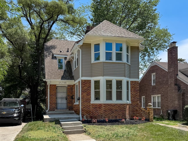 15786 Rutherford St, Detroit, MI 48227 - view of front facade featuring brick siding, a front lawn, and a shingled roof