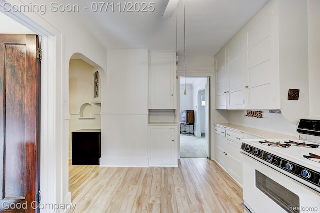 515 W Golden Gate, Detroit, MI 48203 - kitchen with white gas range, light wood-type flooring, white cabinetry, light countertops, and arched walkways