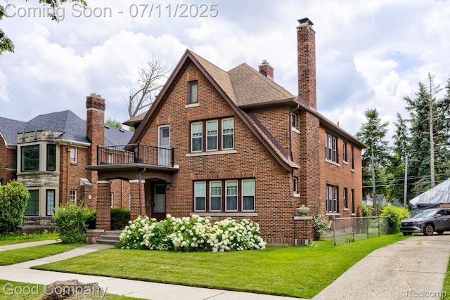 515 W Golden Gate, Detroit, MI 48203 - tudor-style house featuring a balcony, brick siding, a front yard, a chimney, and a shingled roof