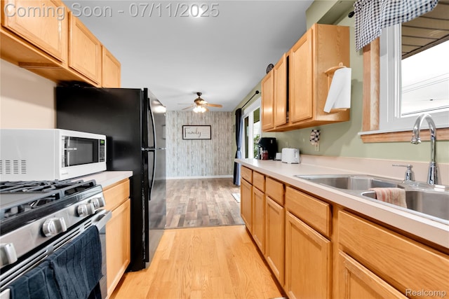 34019 Arrowhead St, Canton, MI 48185 - kitchen with white microwave, stainless steel gas range oven, wallpapered walls, light wood-type flooring, and an accent wall