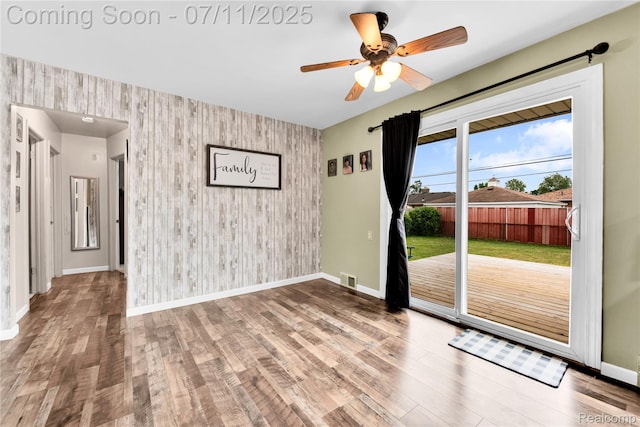 34019 Arrowhead St, Canton, MI 48185 - empty room featuring an accent wall, wallpapered walls, wood finished floors, a ceiling fan, and wooden walls