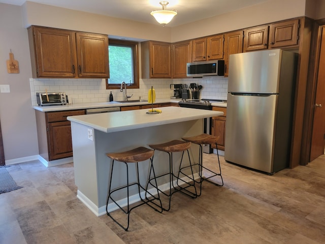 1200 Elmwood Dr, Jenison, MI 49428 - kitchen with stainless steel appliances, a breakfast bar, light countertops, brown cabinetry, and backsplash