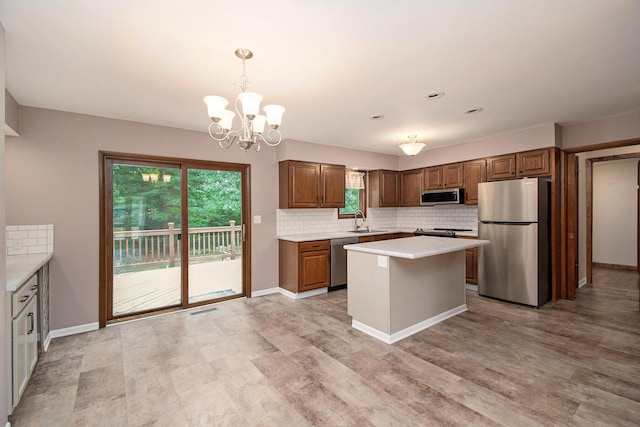 1200 Elmwood Dr, Jenison, MI 49428 - kitchen featuring appliances with stainless steel finishes, light countertops, decorative backsplash, a chandelier, and a center island