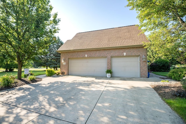 9095 Marsh Cir, Galesburg, MI 49053 - view of side of property featuring brick siding, concrete driveway, an outdoor structure, an attached garage, and roof with shingles