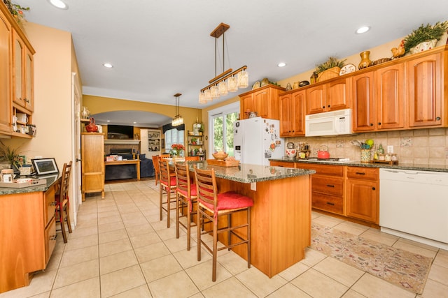 9095 Marsh Cir, Galesburg, MI 49053 - kitchen featuring white appliances, a fireplace, open floor plan, dark stone counters, and a kitchen island