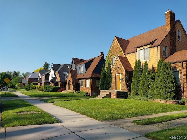 16834 Muirland St, Detroit, MI 48221 - tudor home featuring a residential view, brick siding, a front lawn, and a chimney