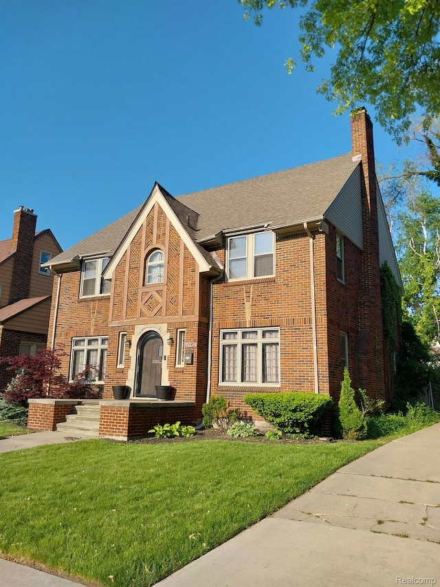 16834 Muirland St, Detroit, MI 48221 - tudor home with a chimney, a front lawn, and brick siding