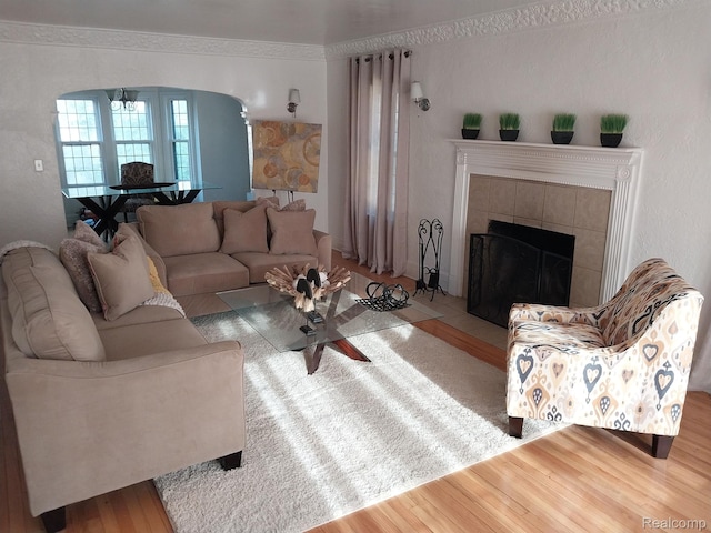 16834 Muirland St, Detroit, MI 48221 - living room with arched walkways, wood finished floors, a tile fireplace, and a chandelier