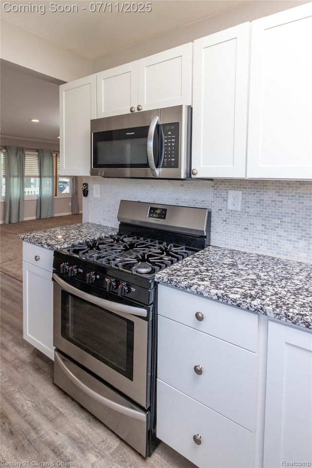 29046 S Wesley Ave, Flat Rock, MI 48134 - kitchen featuring appliances with stainless steel finishes, stone counters, white cabinetry, light wood-type flooring, and decorative backsplash