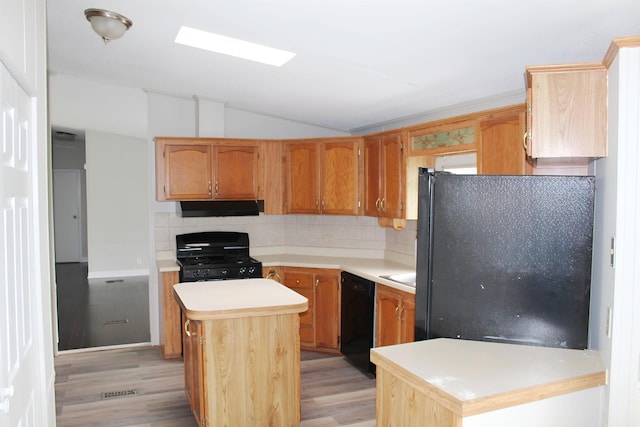 5249 Lapeer Rd, Burton, MI 48509 - kitchen featuring black appliances, under cabinet range hood, light wood-type flooring, vaulted ceiling, and tasteful backsplash