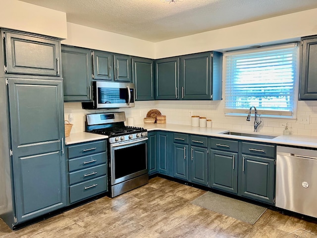 4865 Cactus Dr, Saginaw, MI 48603 - kitchen featuring stainless steel appliances, light countertops, light wood finished floors, tasteful backsplash, and a textured ceiling