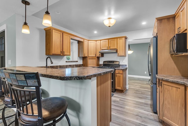 4825 Walz Rd, Jackson, MI 49201 - kitchen featuring stainless steel appliances, under cabinet range hood, a peninsula, dark countertops, and a kitchen breakfast bar